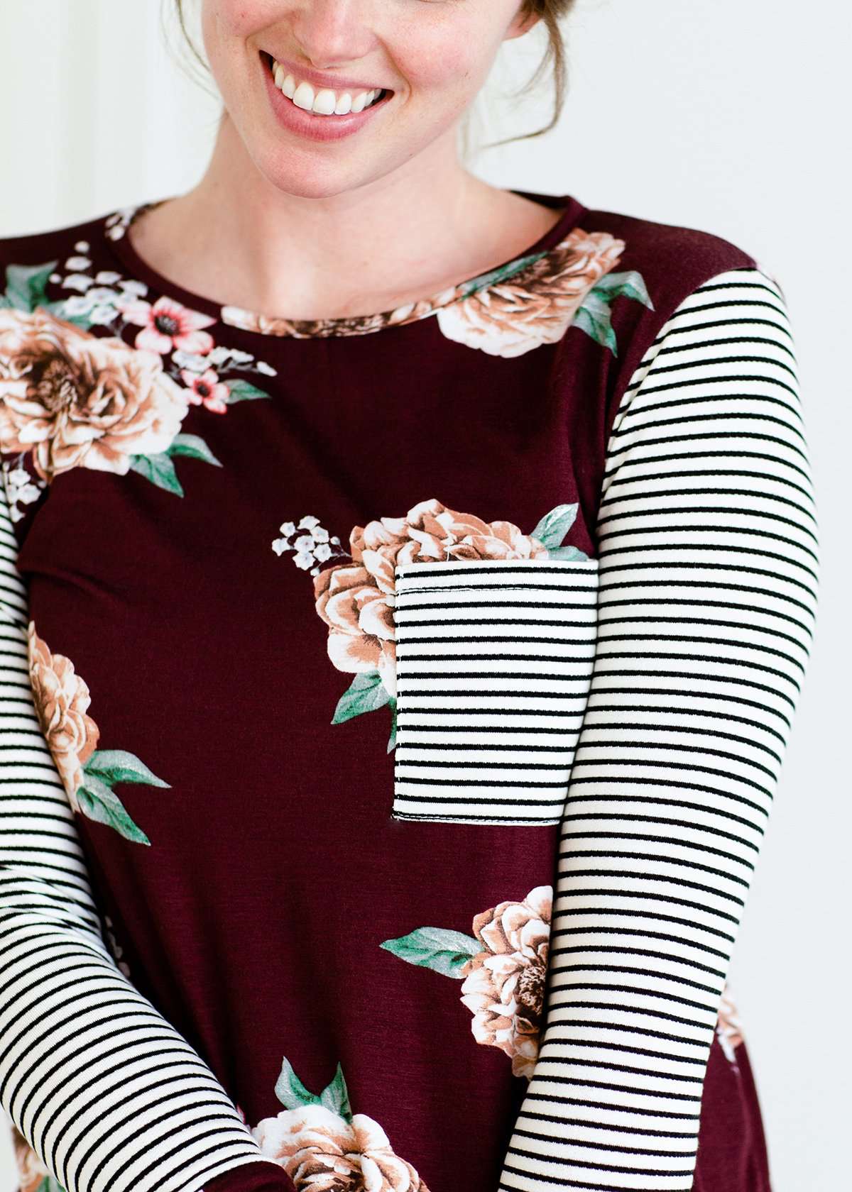 Woman wearing a stripe and floral contrast long sleeve tee with a pocket.