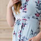 Woman wearing a light blue modest empire waist midi dress with flowers on it
