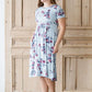 Woman wearing a light blue modest empire waist midi dress with flowers on it