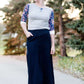 Women wearing a long dark blue denim skirt that is a-line and has flare. This modest skirt is also paired with a floral and gray raglan tee.