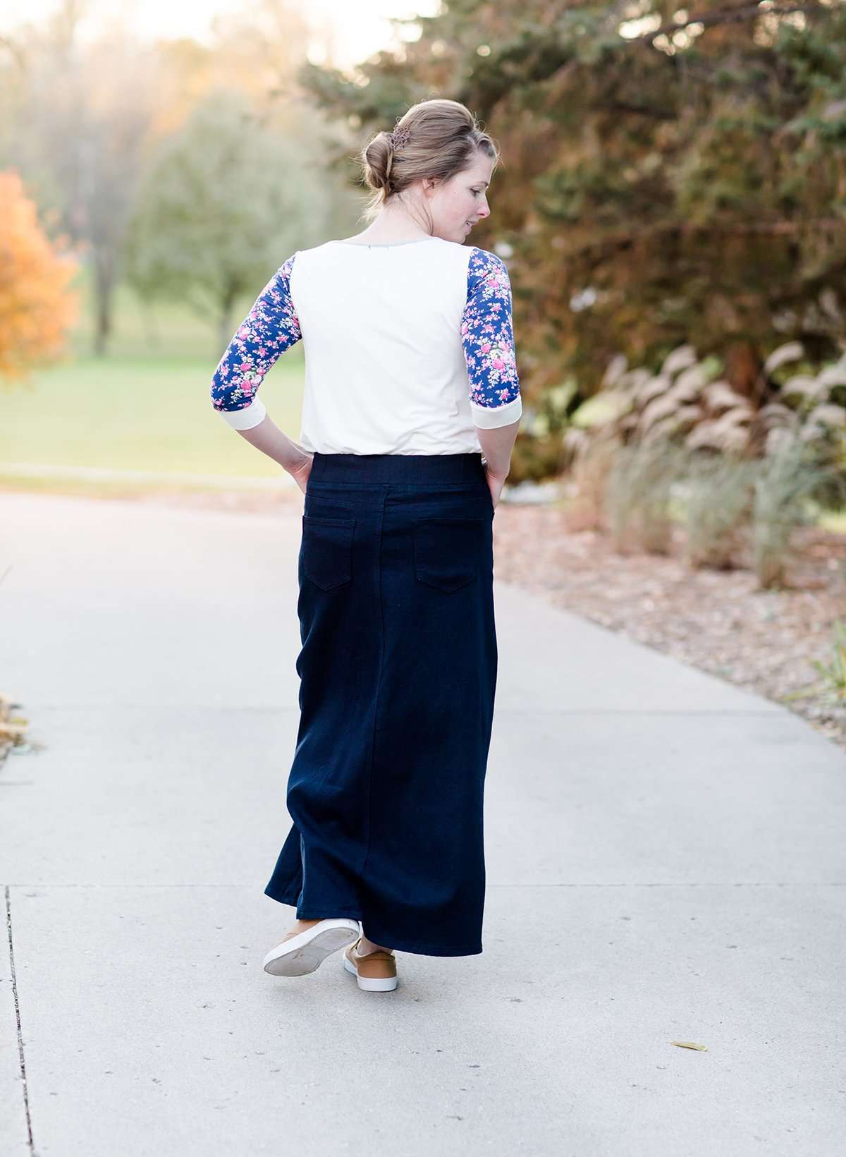 Women wearing a long dark blue denim skirt that is a-line and has flare. This modest skirt is also paired with a floral and gray raglan tee.