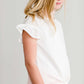 Girl wearing a modest ivory colored tie front top with flutter sleeves