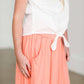 Girl wearing a modest ivory colored tie front top with flutter sleeves