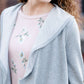 This woman is wearing a tri-blend fleece jacket that is heather gray and has a drape front and shawl collar. 