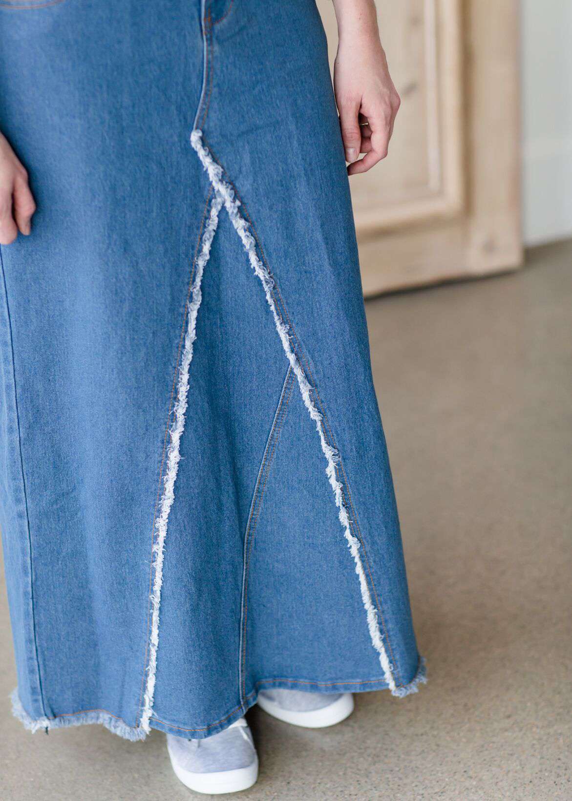 woman wearing an a-line modest long denim skirt with fringe detail and no slit