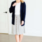 Woman wearing a gray striped skirt with camel colored faux buttons on the front that also has an elastic waistband