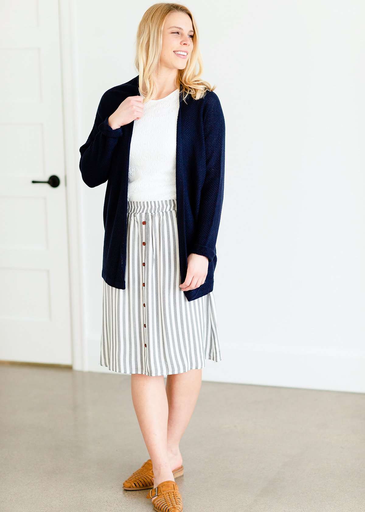 Woman wearing a gray striped skirt with camel colored faux buttons on the front that also has an elastic waistband