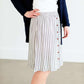 Woman wearing a gray striped skirt with camel colored faux buttons on the front that also has an elastic waistband