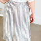 Woman wearing a gray striped skirt with camel colored faux buttons on the front that also has an elastic waistband