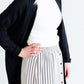 Woman wearing a gray striped skirt with camel colored faux buttons on the front that also has an elastic waistband