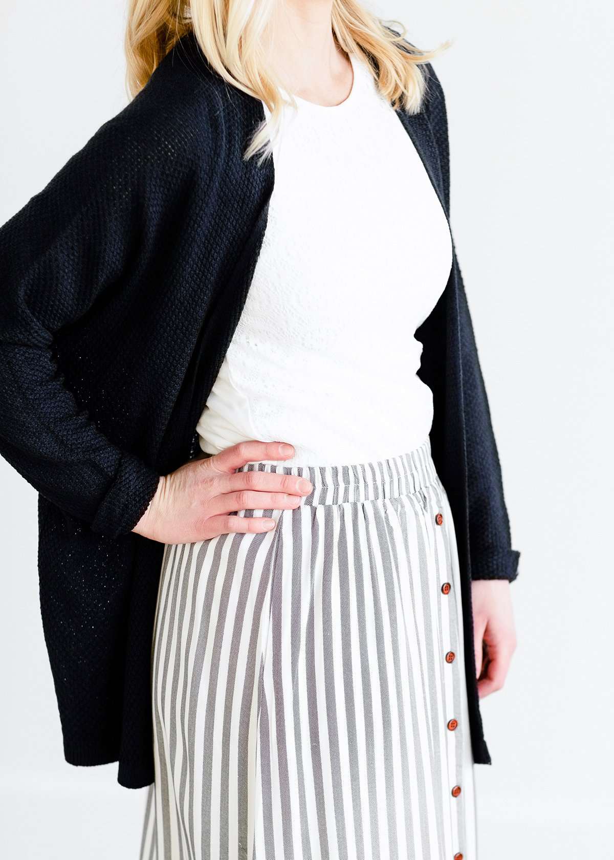 Woman wearing a gray striped skirt with camel colored faux buttons on the front that also has an elastic waistband