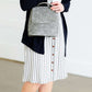 Woman wearing a gray striped skirt with camel colored faux buttons on the front that also has an elastic waistband