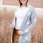 Young woman wearing a modest, long, polka dot, gray, open front cardigan. She is also wearing a khaki corduroy below the knee skirt.