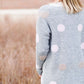Young woman wearing a modest, long, polka dot, gray, open front cardigan. She is also wearing a khaki corduroy below the knee skirt.