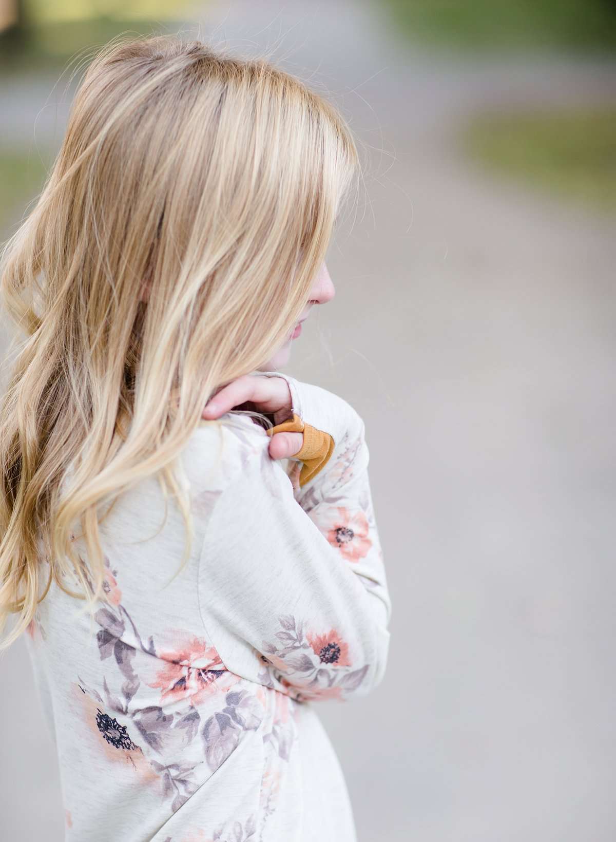 Young girl wearing a modest floral sweatershirt with blush and gold and also thumb holes on the modest sweatshirt