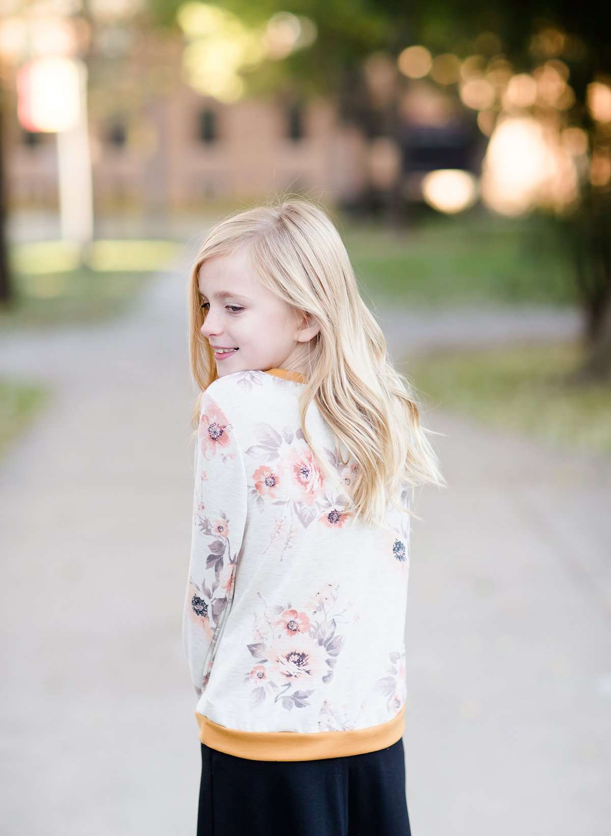 Young girl wearing a modest floral sweatershirt with blush and gold and also thumb holes on the modest sweatshirt