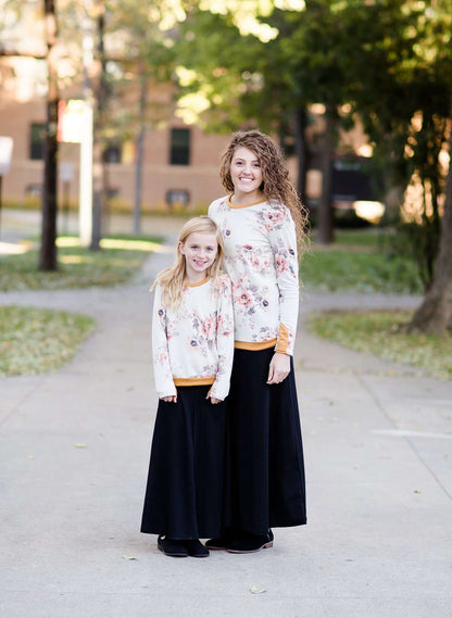 Woman and daughter wearing a blush floral modest sweatshirt with thumbholes that is lined with a mustard trim