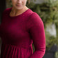 Woman wearing a wine colored maxi dress made of a hacci material standing outside of Inherit Clothing Company
