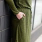 Woman wearing a olive colored hacci midi dress with a elastic waist and paired with black sole society boots