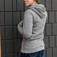 Triblend Minnesota hoodie on a young woman, the hoodie is navy with a gold MN emblem on front and gray with a purple MN emblem on front.