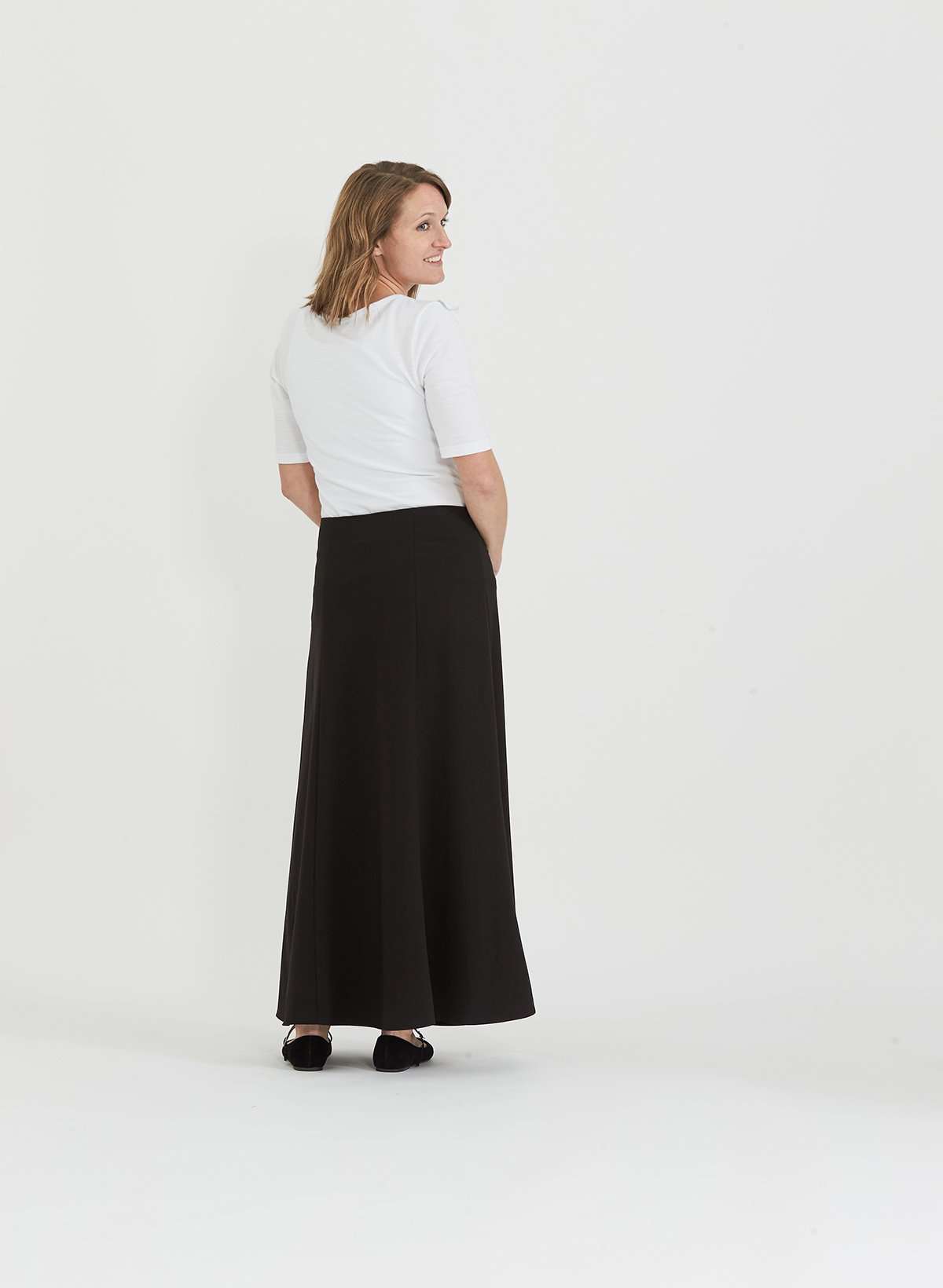 Woman wearing a black, dressy church skirt with panels and a side zipper. This long skirt has panels and a flowy bottom as well.