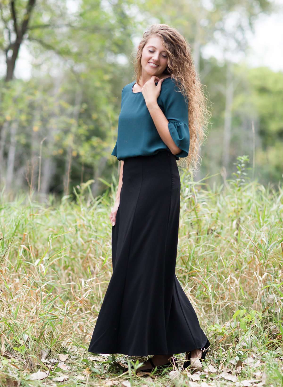 Woman wearing a black, dressy church skirt with panels and a side zipper. This long skirt has panels and a flowy bottom as well.