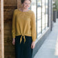Woman wearing a mustard tie front top with back buttons