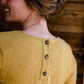 Woman wearing a mustard tie front top with back buttons