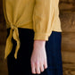 Woman wearing a mustard tie front top with back buttons