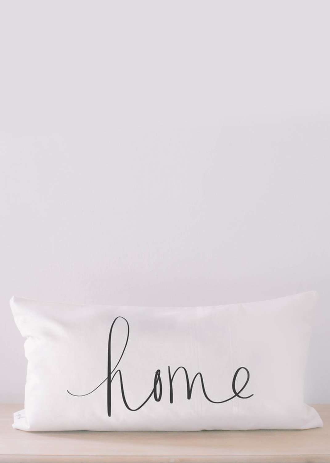 White lumbar pillow with the words home on it