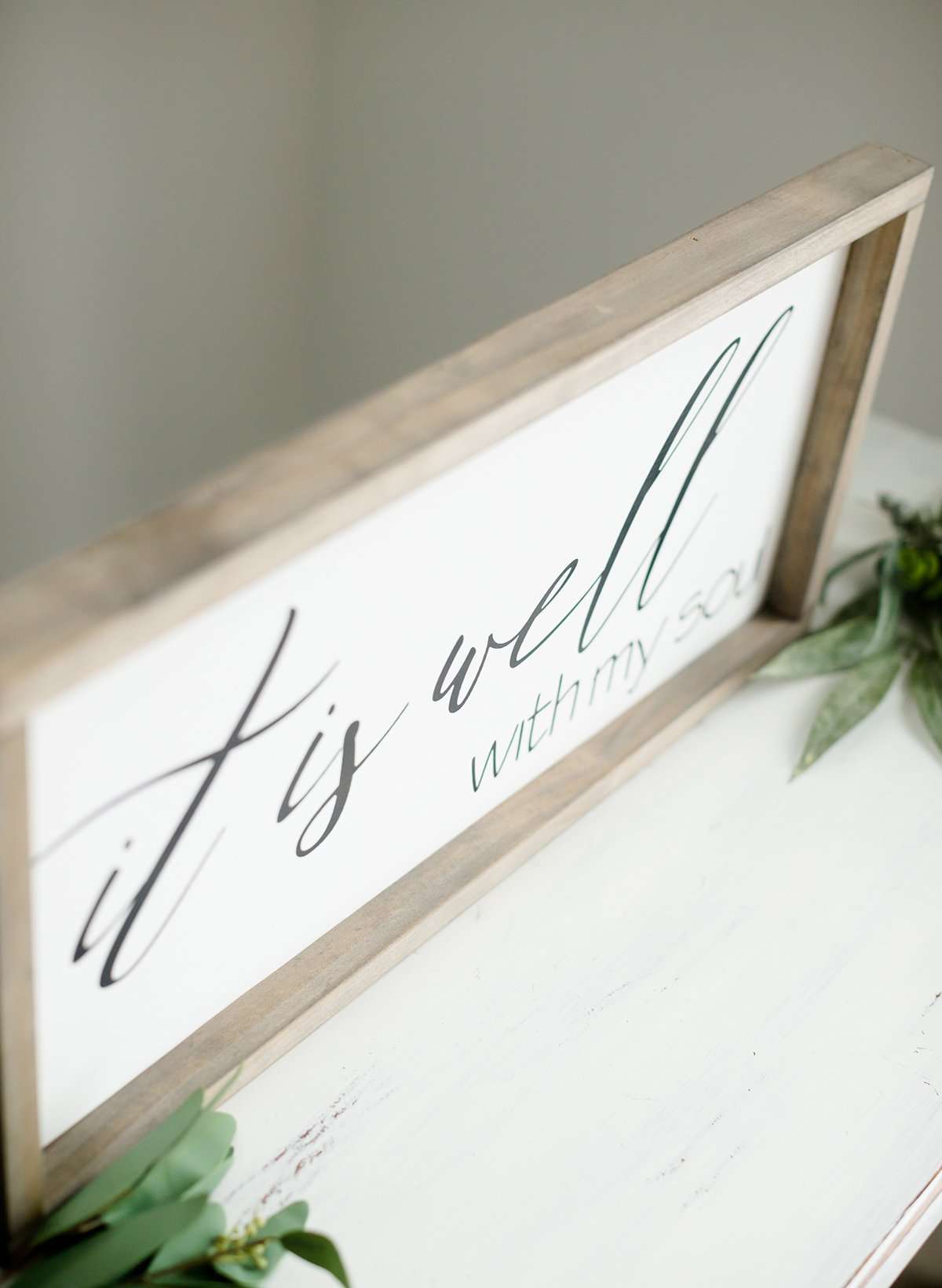 Wood Frame Signboard with the words" It is well with my soul" printed on it in black script font.