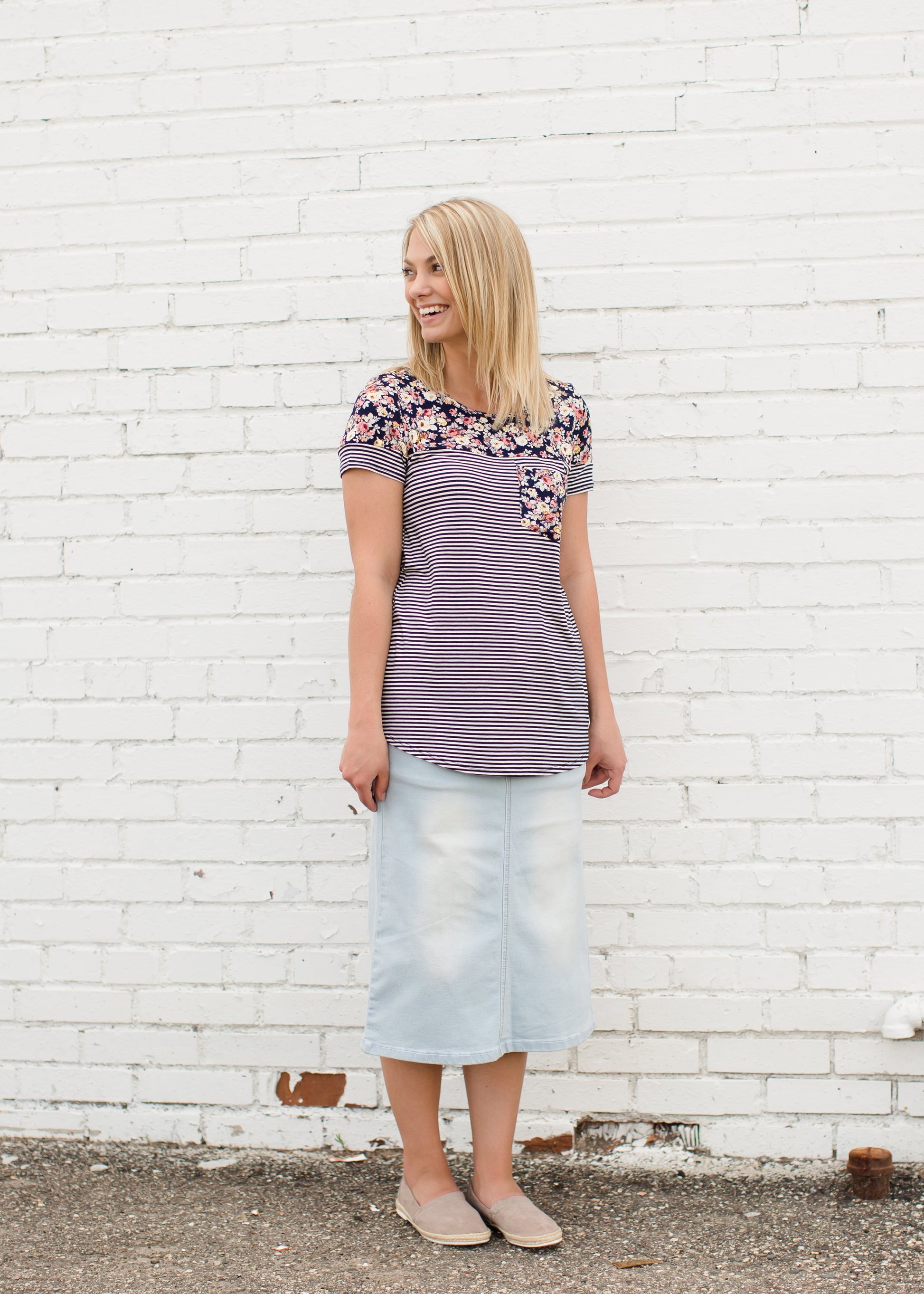 Young lady wearing a light denim below the knee jean skirt.