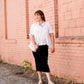 Woman wearing a straight style, ultra soft versatile black midi skirt.