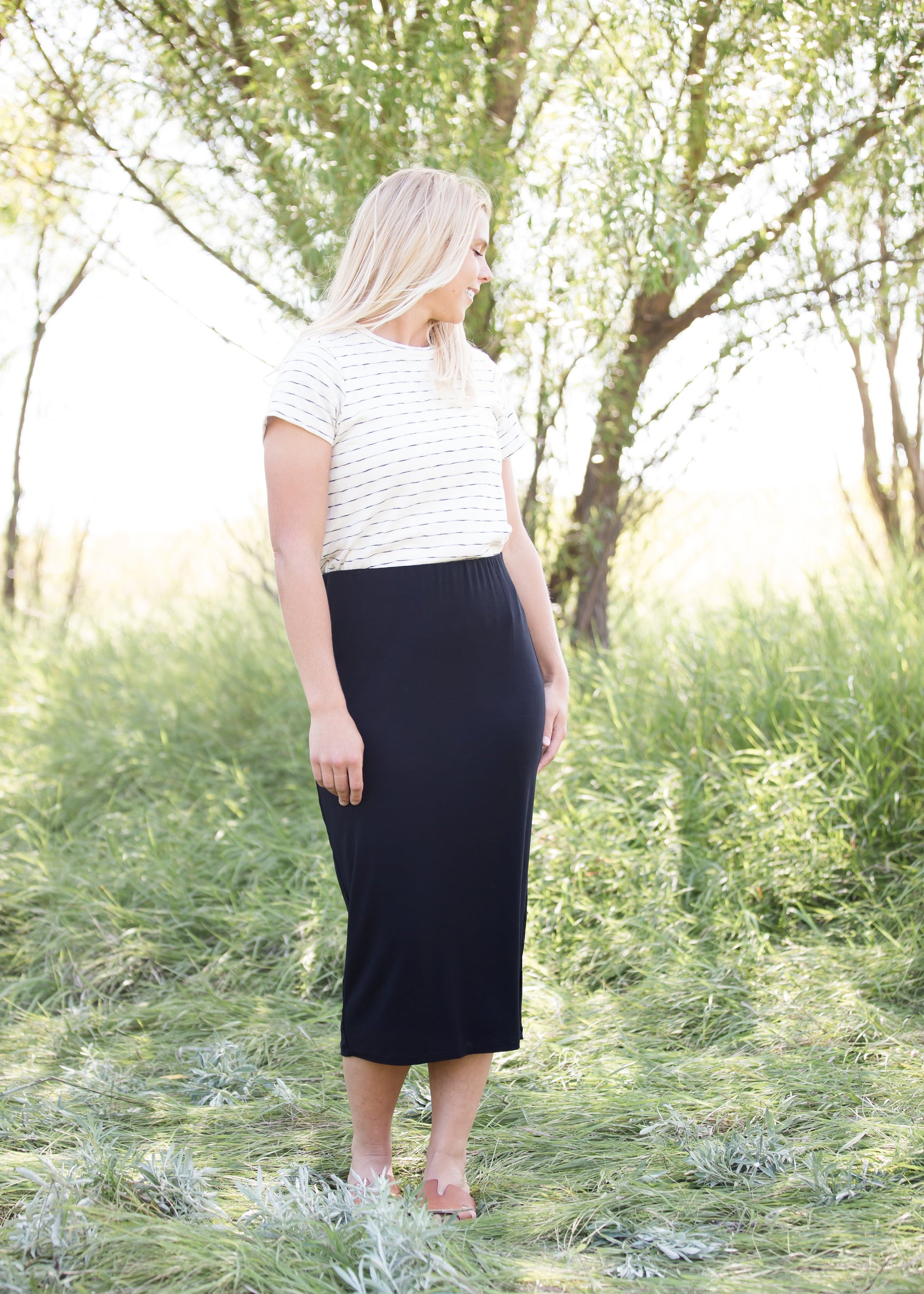Woman wearing a straight style, ultra soft versatile black midi skirt.