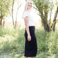 Woman wearing a straight style, ultra soft versatile black midi skirt.