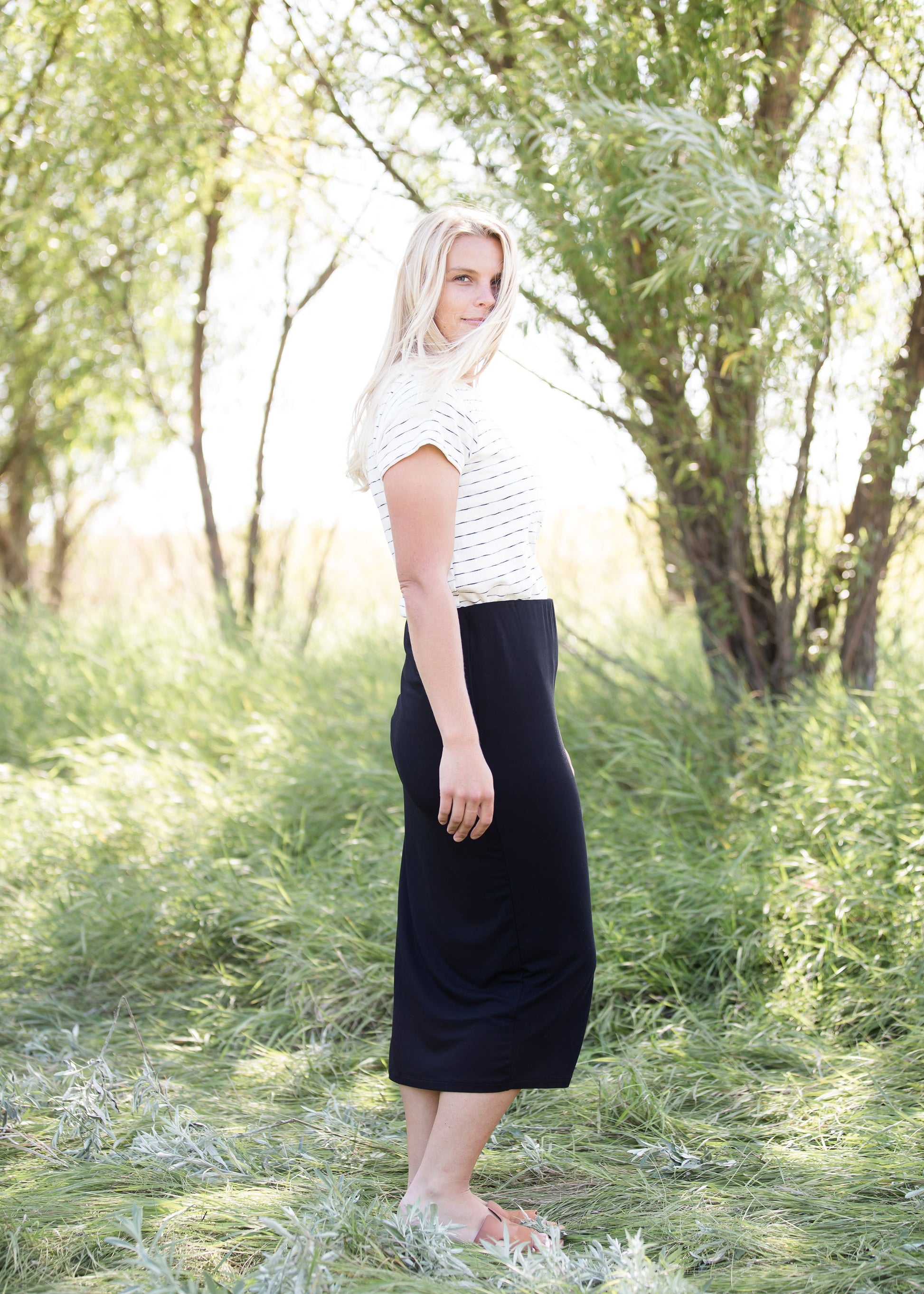 Woman wearing a straight style, ultra soft versatile black midi skirt.