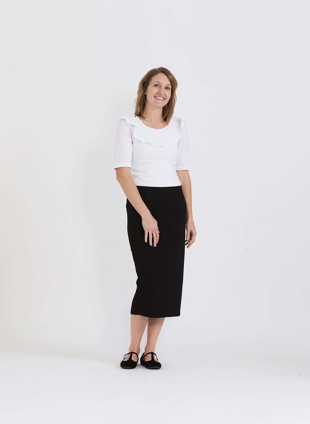 Woman wearing a straight style, ultra soft versatile black midi skirt.