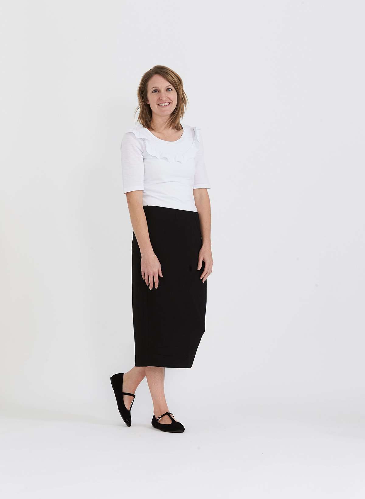 Woman wearing a straight style, ultra soft versatile black midi skirt.