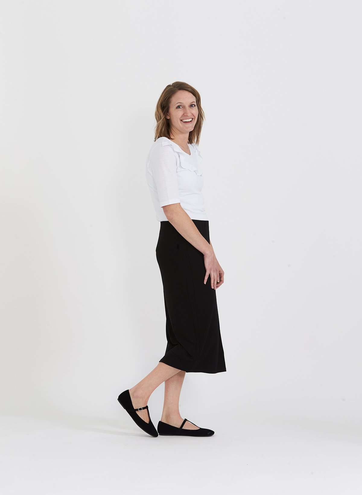 Woman wearing a straight style, ultra soft versatile black midi skirt.