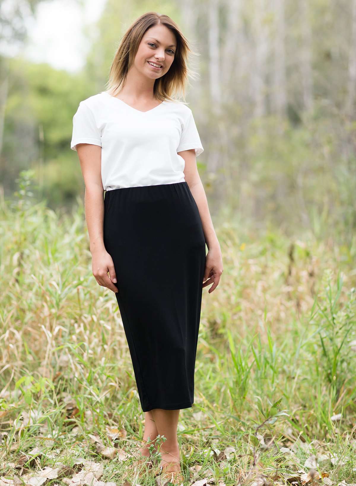 Woman wearing a straight style, ultra soft versatile black midi skirt.