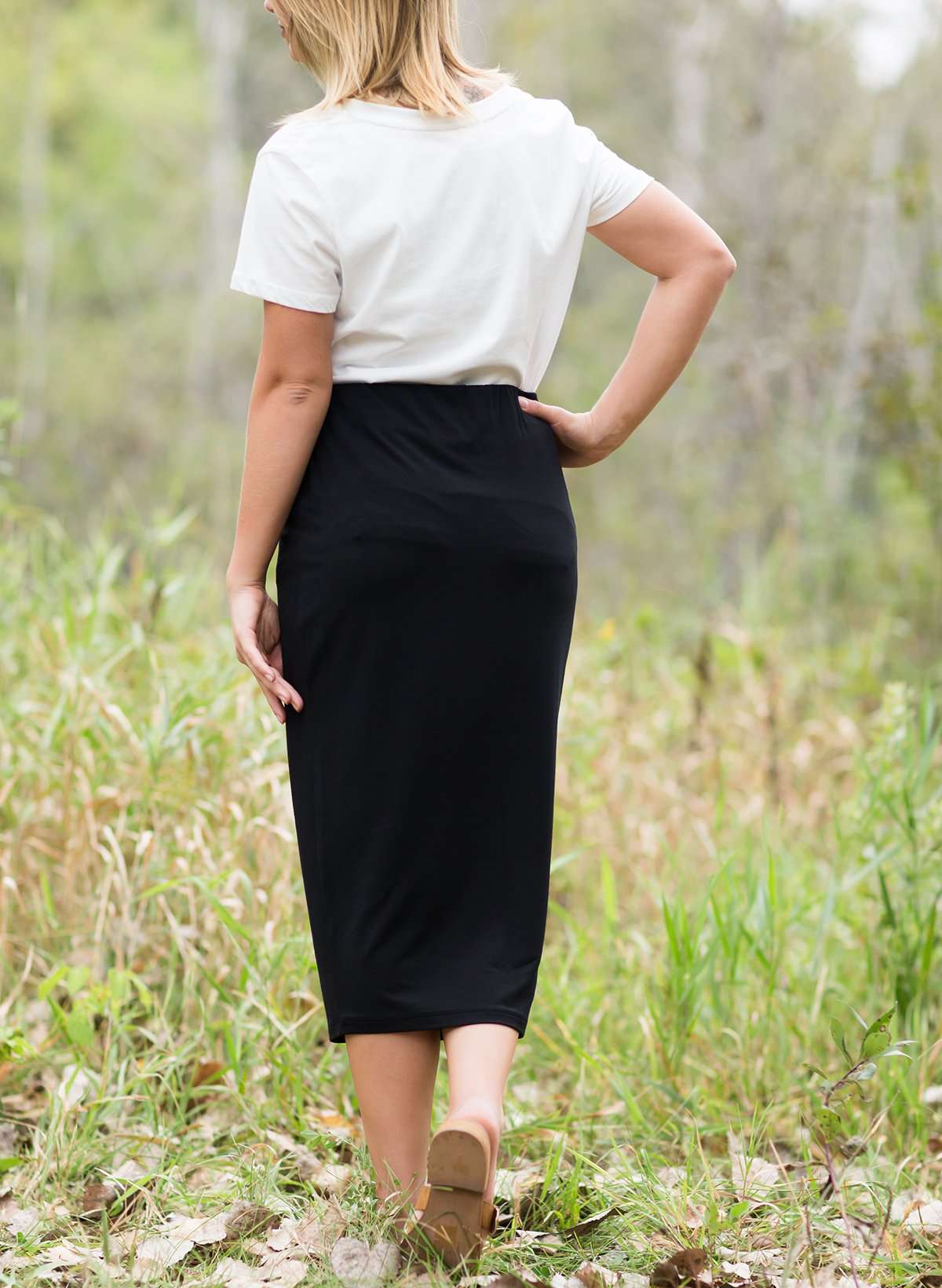 Woman wearing a straight style, ultra soft versatile black midi skirt.