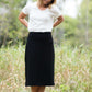 Woman wearing a straight style, ultra soft versatile black midi skirt.