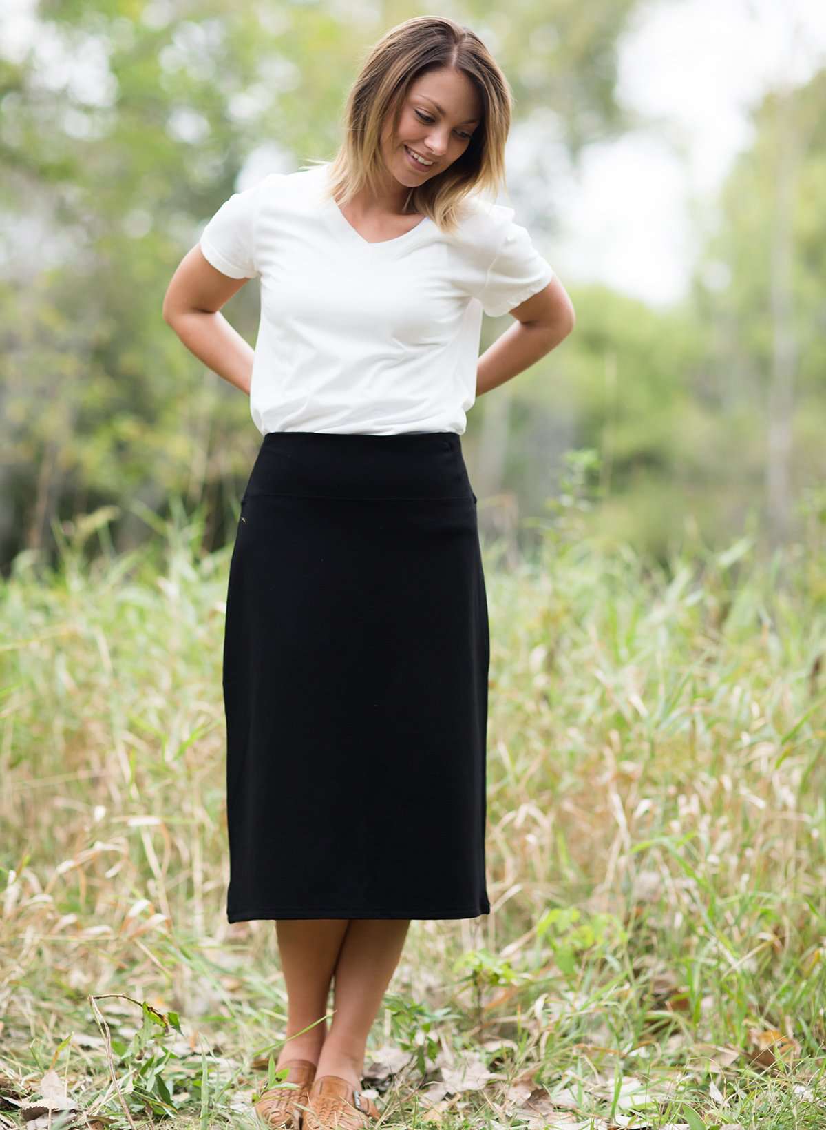 Woman wearing a straight style, ultra soft versatile black midi skirt.