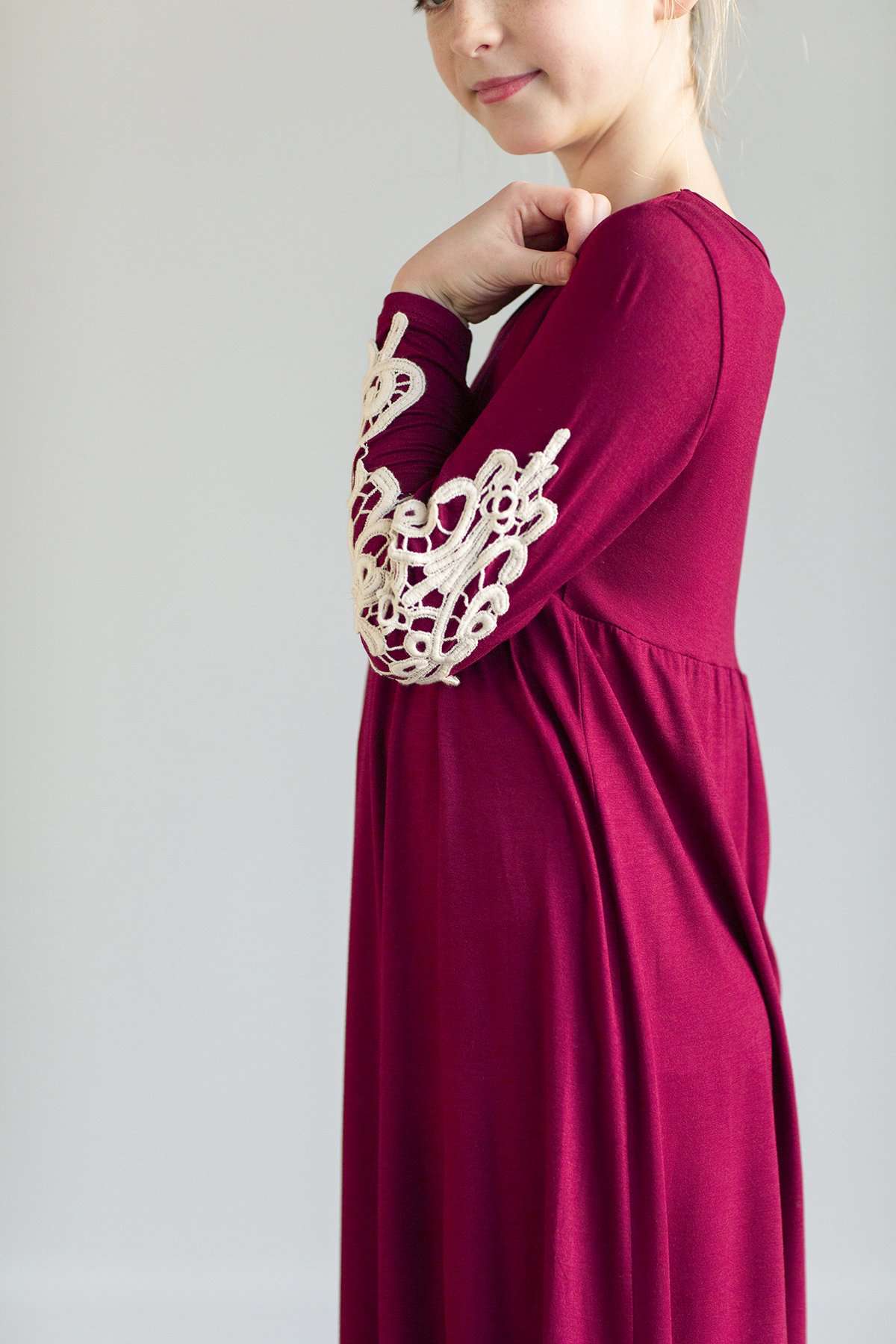 Young girl wearing a burgandy maxi dress with crochet detail.