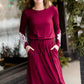 Woman wearing a burgandy and lace midi dress with black tights and sole society back boots. She is standing outside of Inherit Clothing Company.