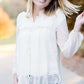 Young woman wearing a vintage inspired ruffle and layered cream colored blouse. This blouse features ruffles and ribbon details.