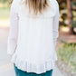 Young woman wearing a vintage inspired ruffle and layered cream colored blouse. This blouse features ruffles and ribbon details.