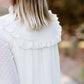Young woman wearing a vintage inspired ruffle and layered cream colored blouse. This blouse features ruffles and ribbon details.
