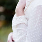 Young woman wearing a vintage inspired ruffle and layered cream colored blouse. This blouse features ruffles and ribbon details.