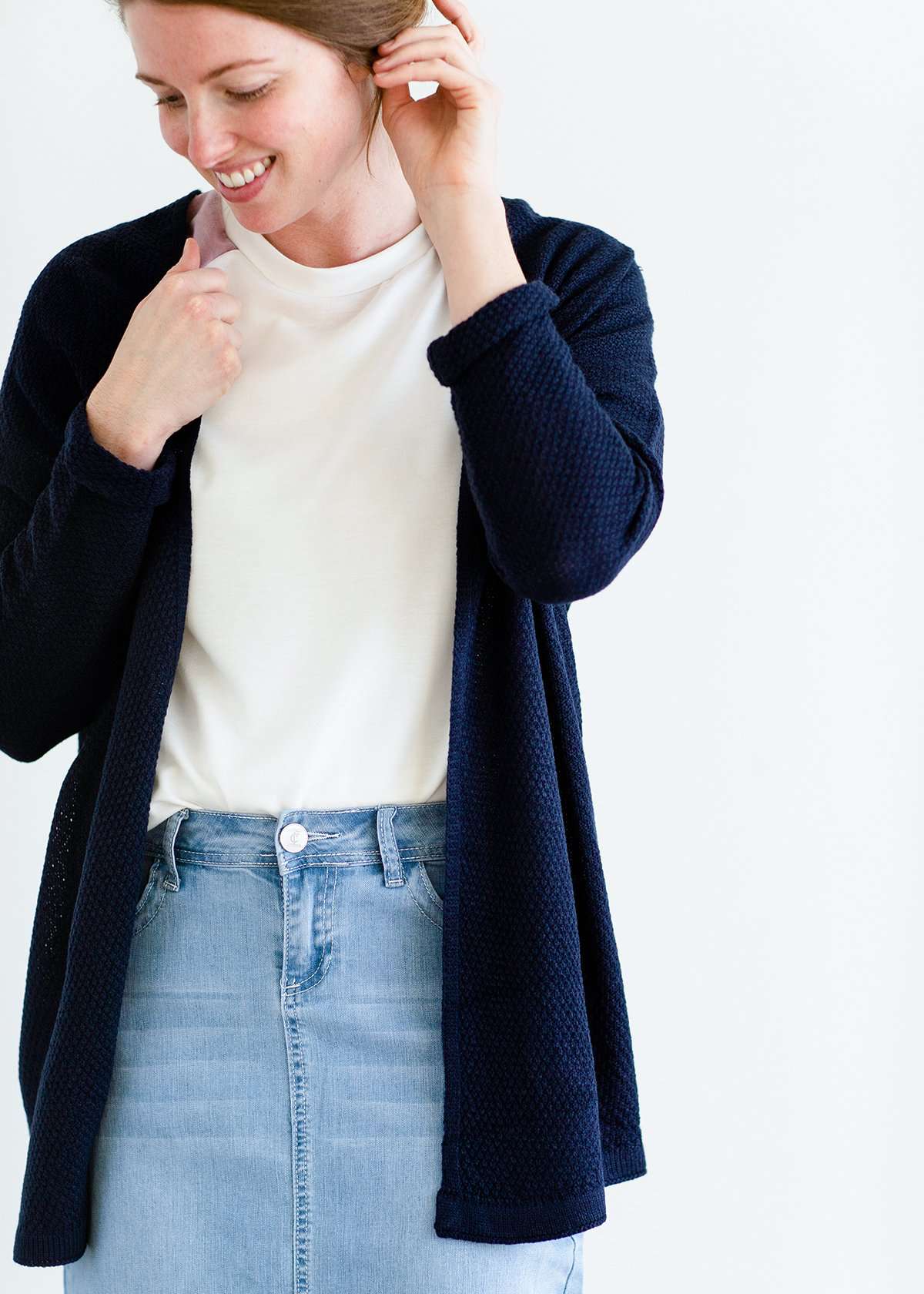 Woman wearing a lightweight knit cardigan in navy, taupe or cream. 